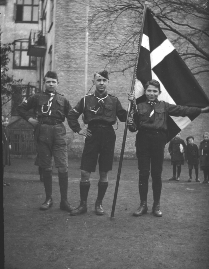 Tre spejdere fra Dansk Spejderkorps Sydslesvig med Dannebrog, 1920'erne. Tre spejdere fra Dansk Spejderkorps Sydslesvig med Dannebrog, 1920'erne.